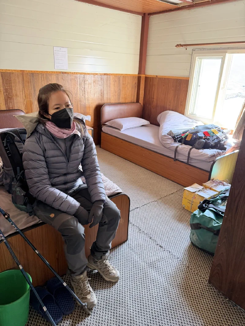 Pokin sitting on bed in lodge room looking exhausted