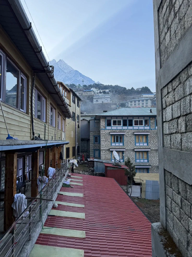 Snow-capped peak framed between village buildings with laundry drying