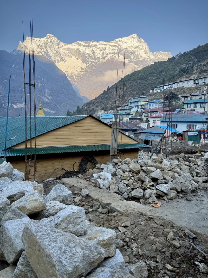 Construction stones and stupa spire with Namche terraced behind and snow peaks