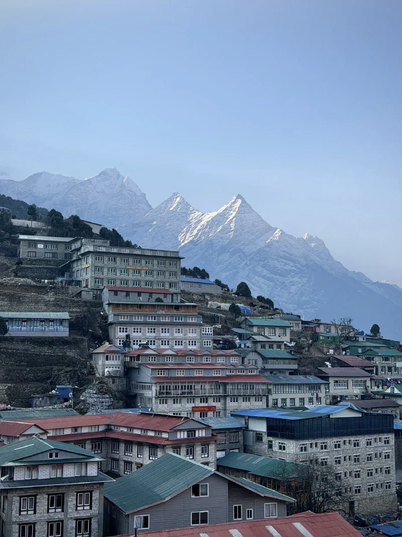 Wide view of Namche Bazaar amphitheater with colorful buildings and Himalayan peaks