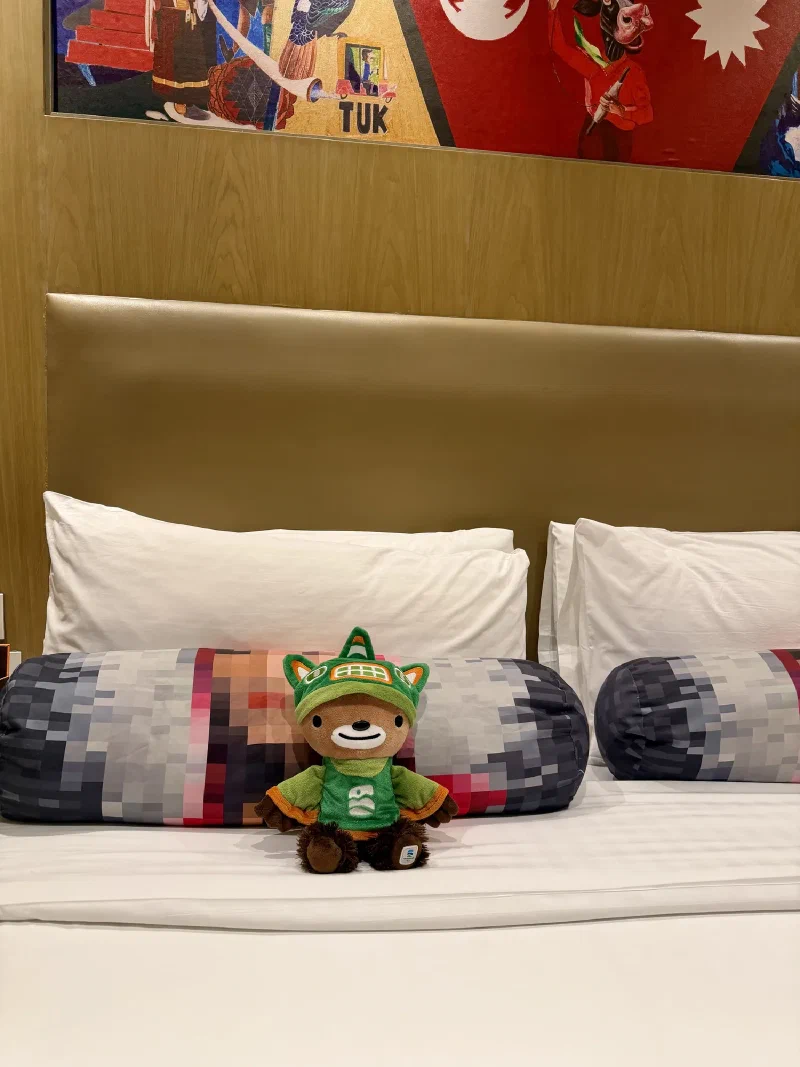 Sumi sitting on the hotel bed between two pillows