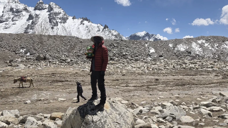 Nicholas standing on a rock holding Sumi with glacier landscape behind