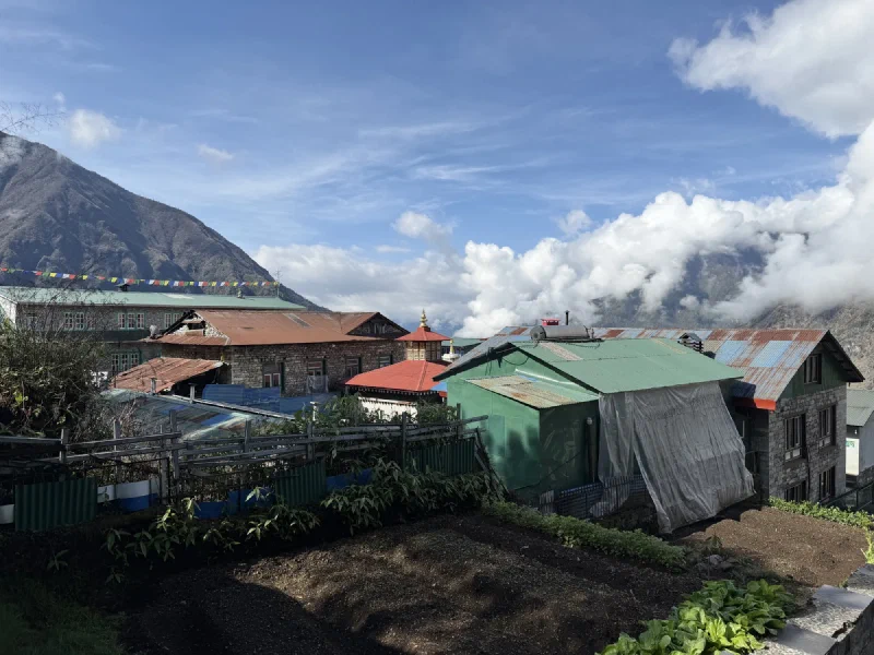 A back alley of Lukla town with prayer flags and mountains behind