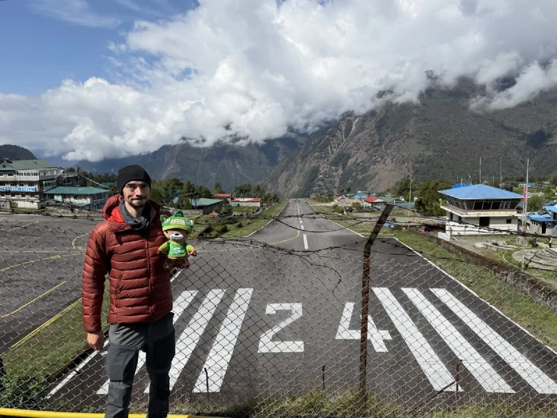 Nicholas holding Sumi at the fence overlooking the sloped Lukla Airport runway