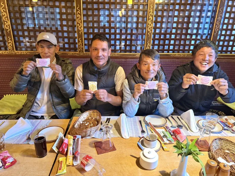 Four porters smiling and holding up packets of cookies at the dinner table