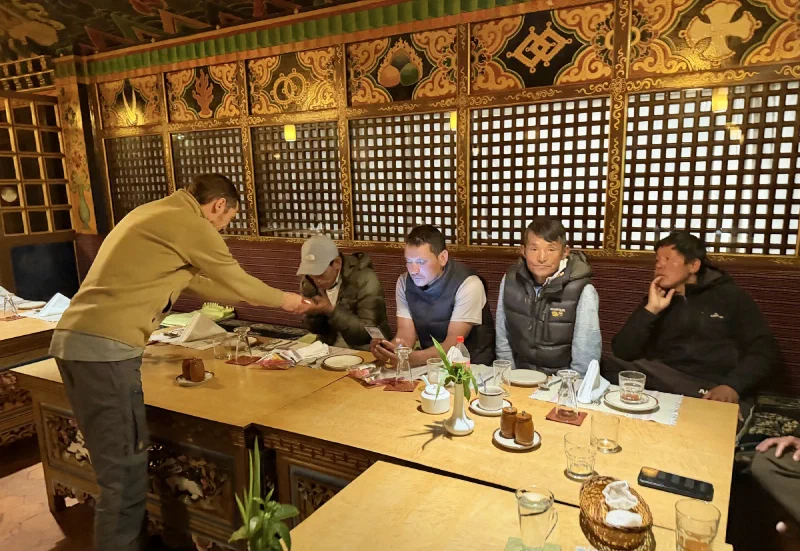 Nicholas handing red envelopes of cash tips to the seated porters