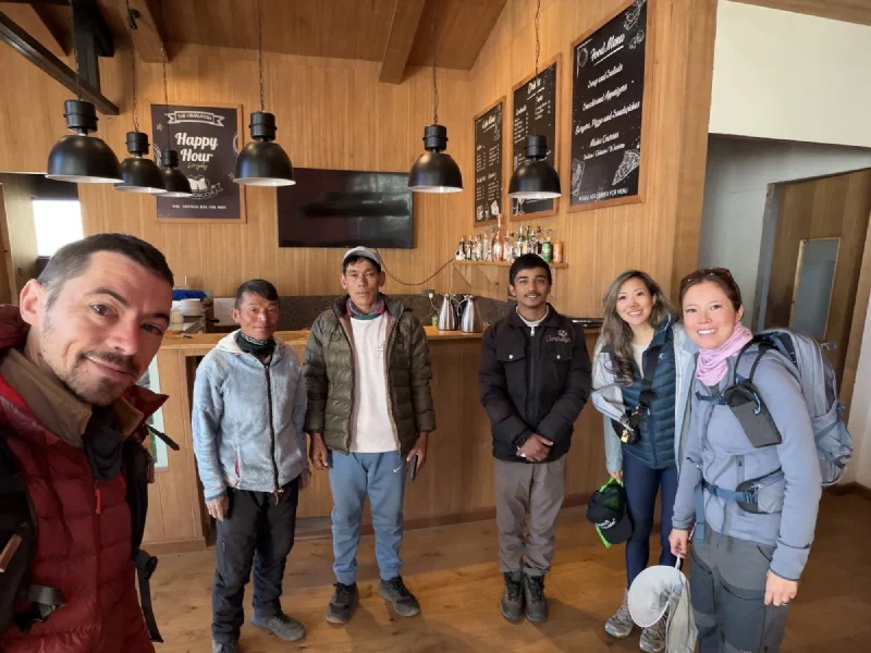Group photo inside a lodge with warm wooden walls, six people smiling together