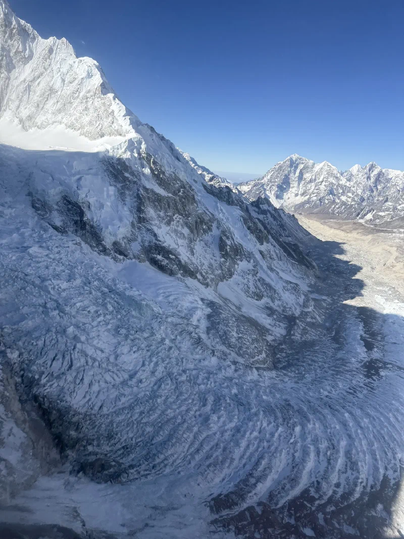 Aerial view of the Khumbu Icefall showing chaotic blue-white glacial ice, crevasses, and steep mountain walls