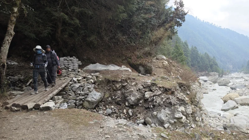 Pokin and Manoj crossing a log bridge on the trail