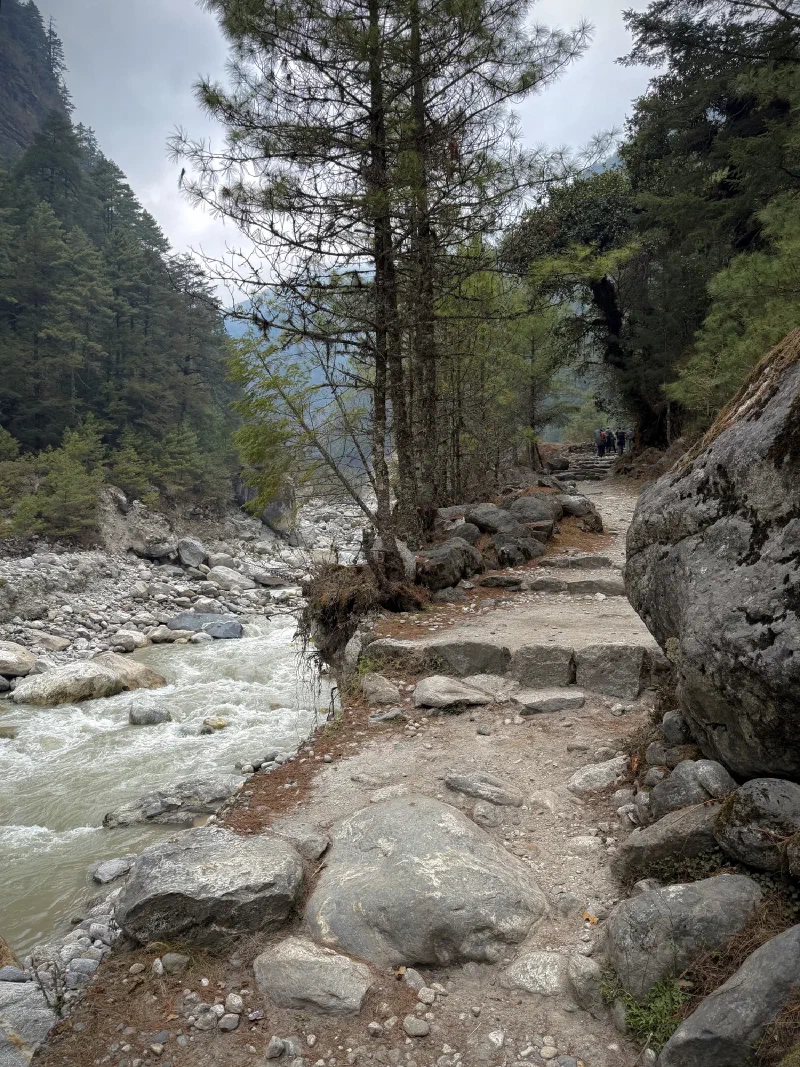 Trail along the river with trekkers in the distance