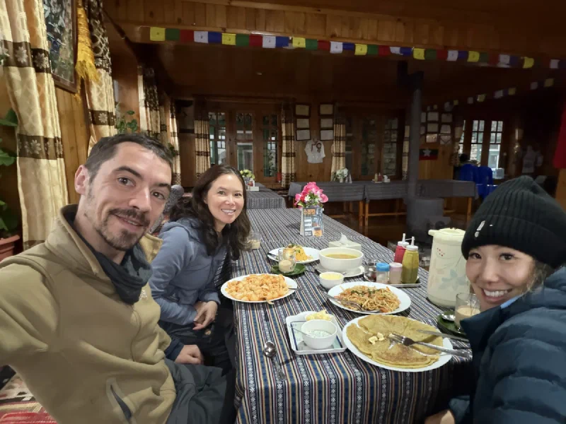 Nicholas, Pokin, and Po On smiling around a full table of food at the Yak Hotel