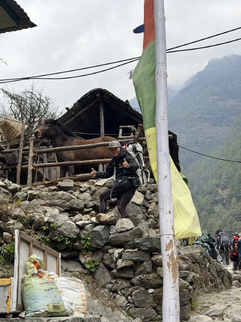 D.B. giving double thumbs up with a horse visible in a stable behind him