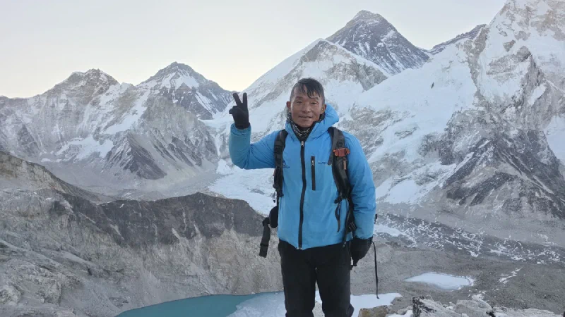 Kerman on the summit of Kala Patthar giving a peace sign with Everest behind