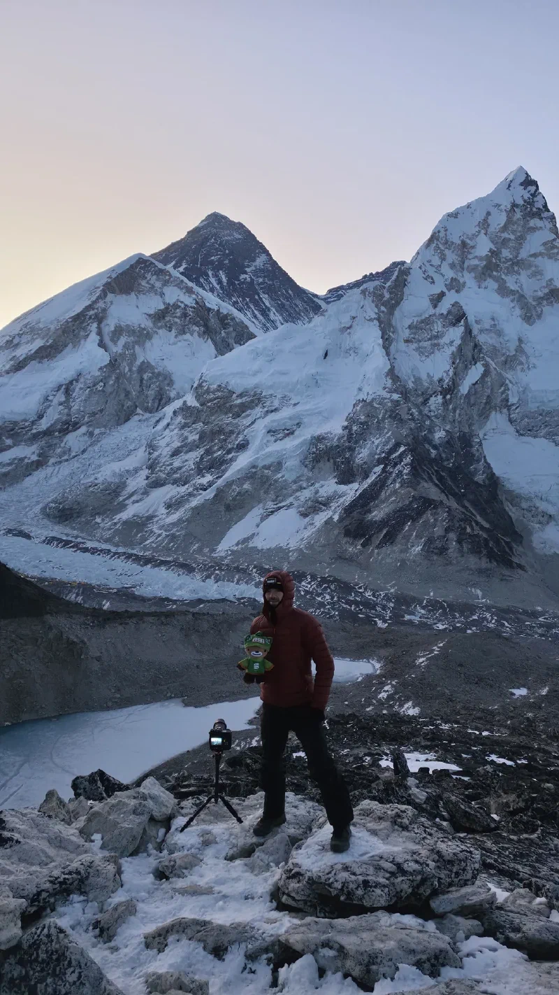Nicholas holding Sumi on the summit with Everest and frozen lake below