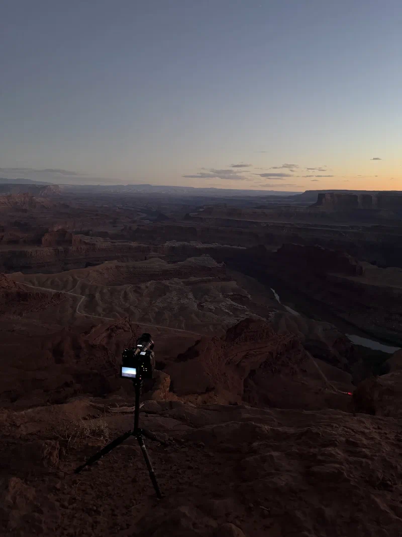 A camera on a tripod overlooking the canyon in deep blue hour light