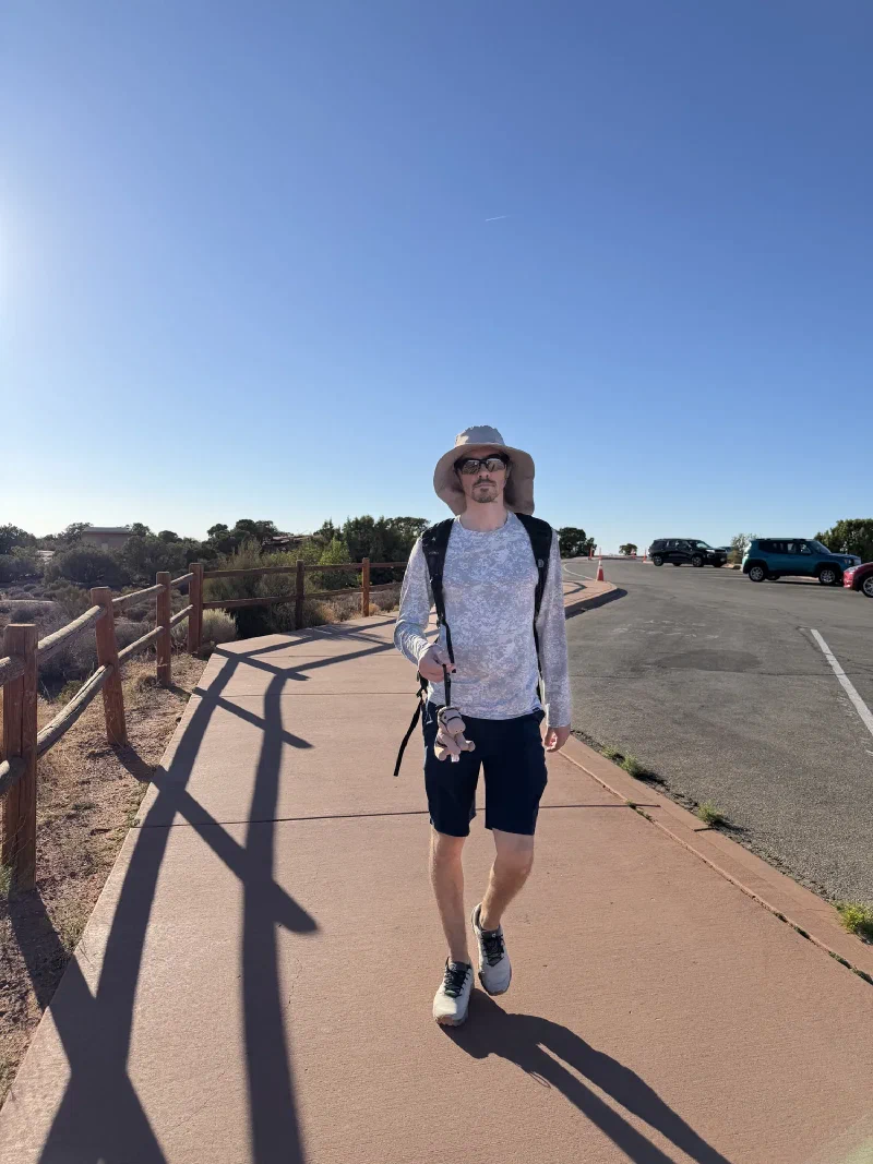 Nicholas walking up a paved path from the car park carrying Chestnut by a strap