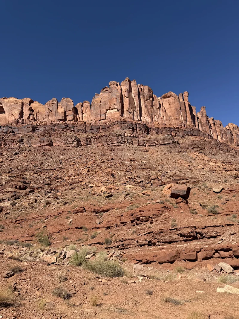 Layered red cliff bands rising above a rocky slope