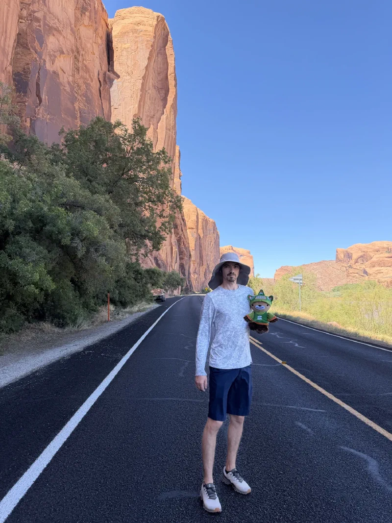 Nicholas holding Sumi on a two-lane road beneath an enormous red sandstone wall