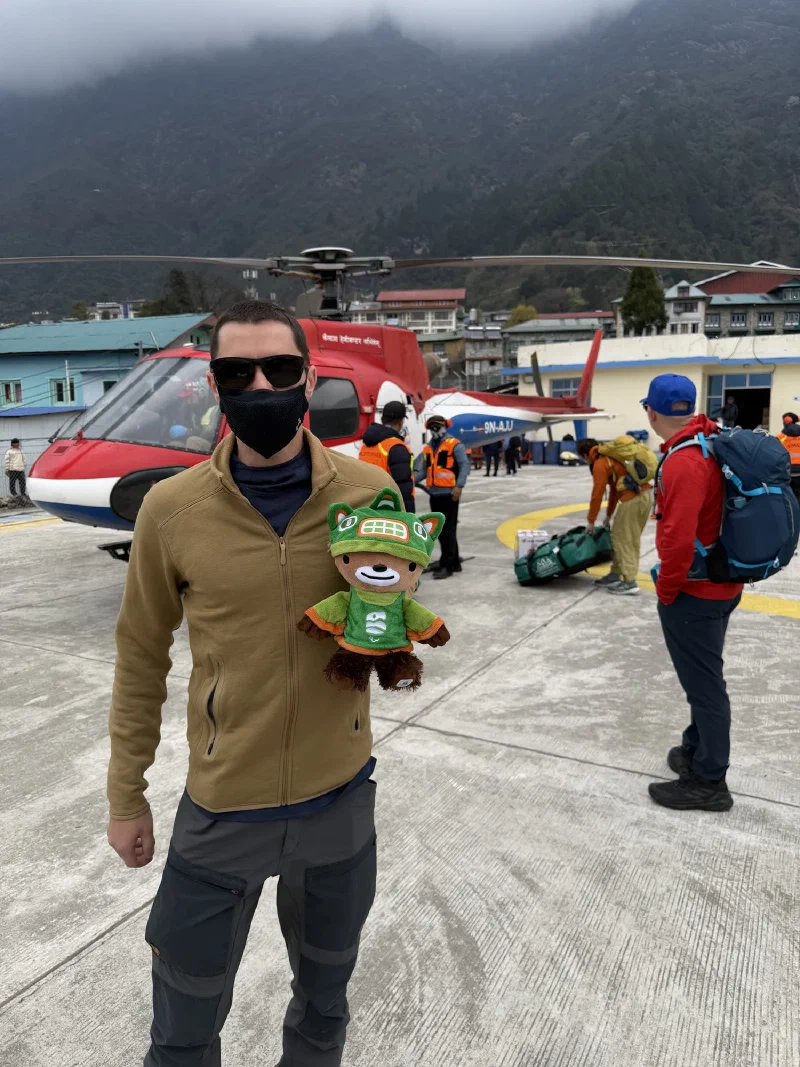 Nicholas holding Sumi on the Lukla tarmac while the helicopter is unloaded