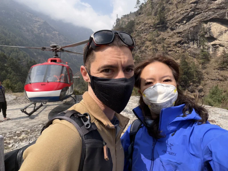 Nicholas and Pokin selfie after landing in Phakding with the helicopter and valley cliffs behind them