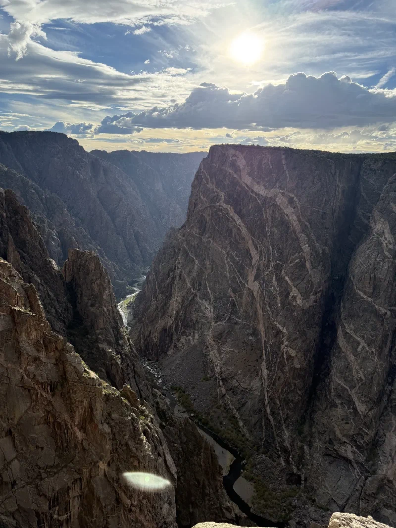 A wide view of the gorge with bright zig-zagging pale veins running through the dark canyon walls
