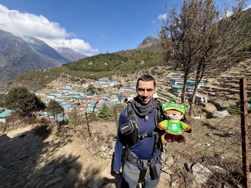 Nicholas on trail with Sumi Bear in backpack strap and Namche amphitheater behind