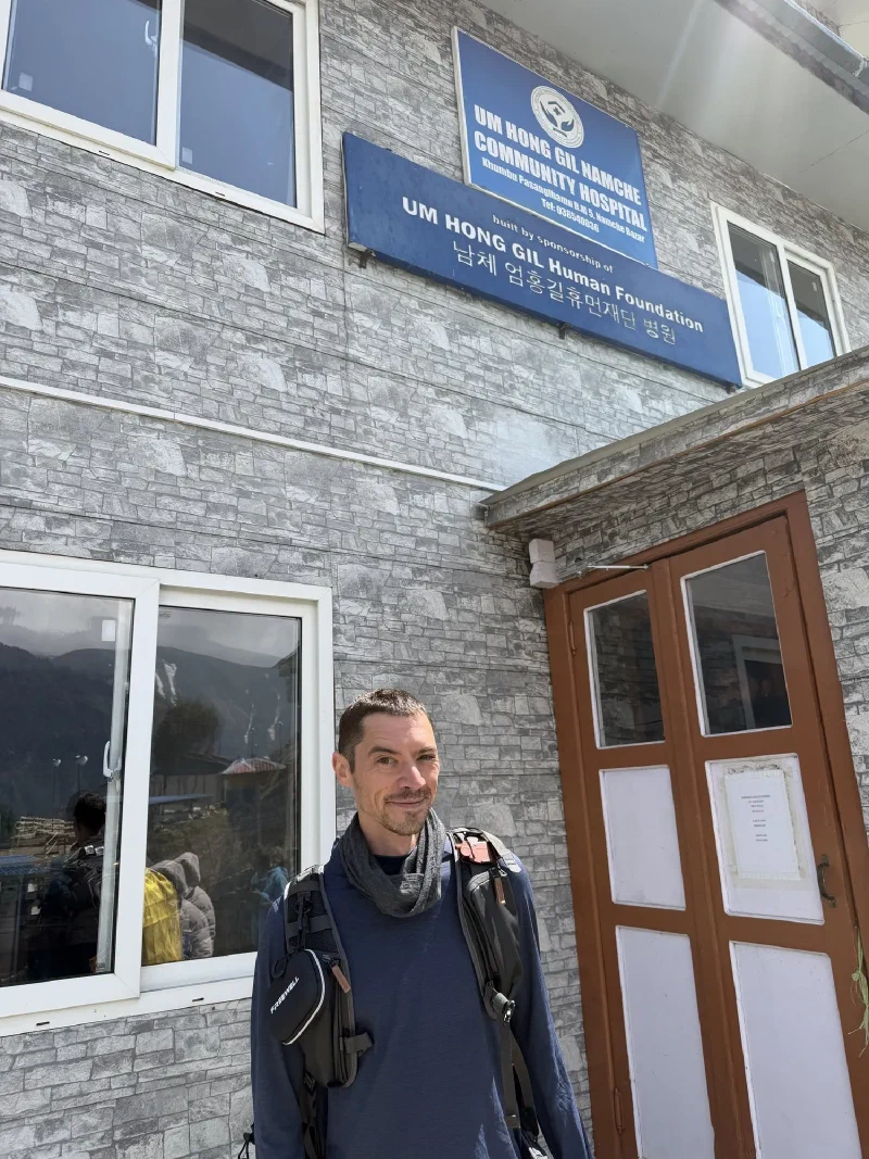 Nicholas outside Um Hong Gil Namche Community Hospital with sign in English and Korean