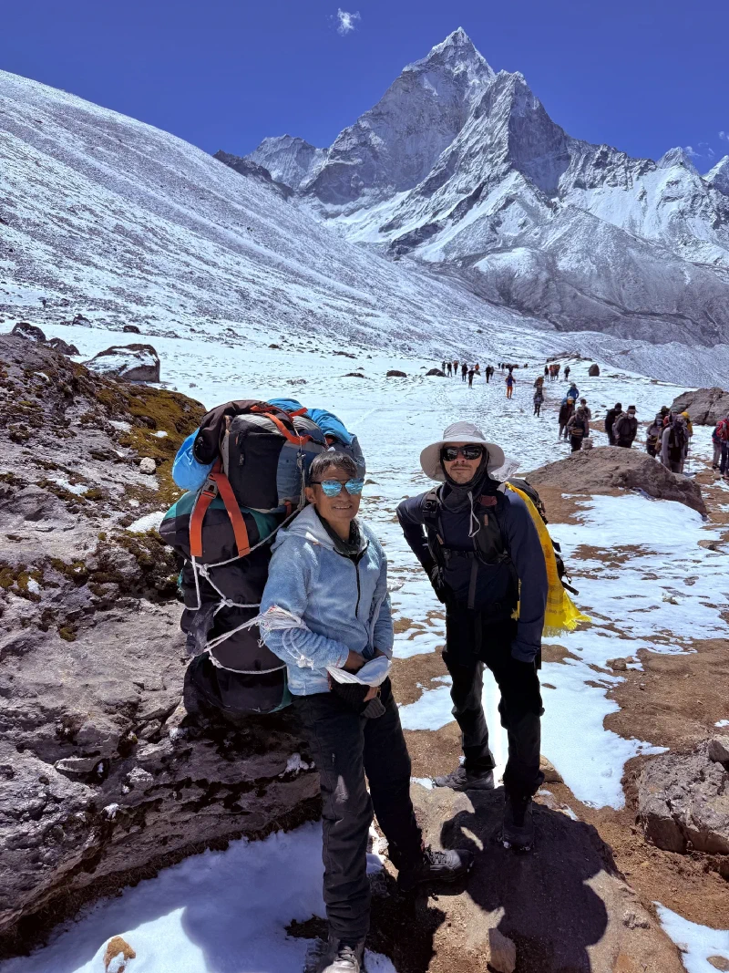 Nicholas and Kerman walking on a snowy trail with mountains behind