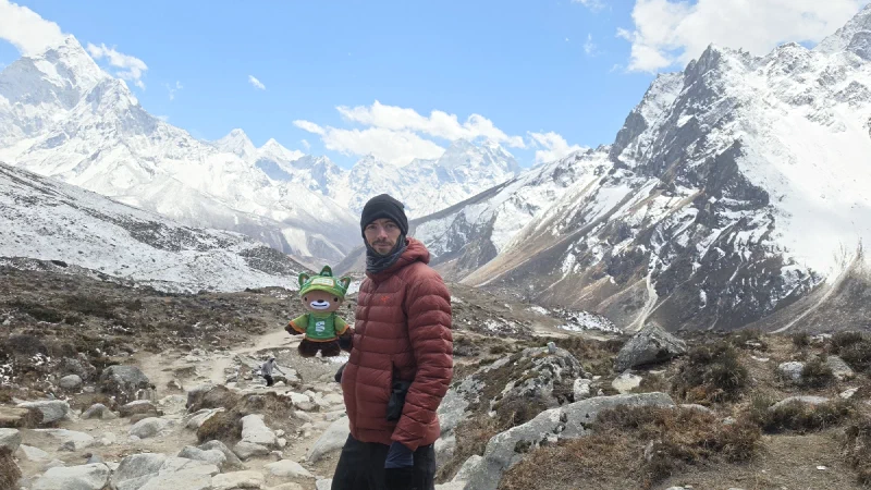 Nicholas holding Sumi on the trail with valley stretching behind