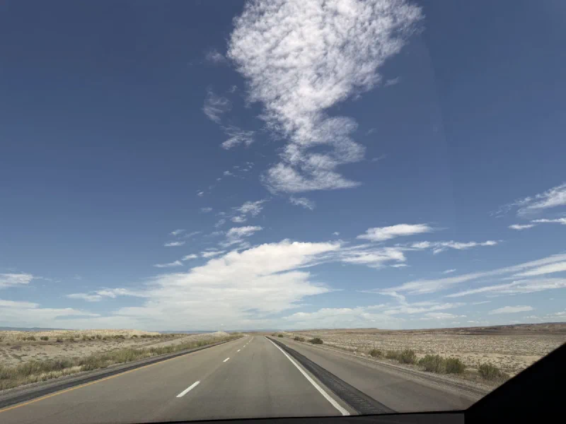 A wide empty interstate running east through pale desert under a big sky