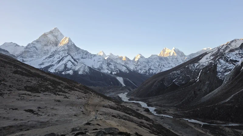 Wide view of the Himalayan valley at sunrise with snow-covered peaks catching first light