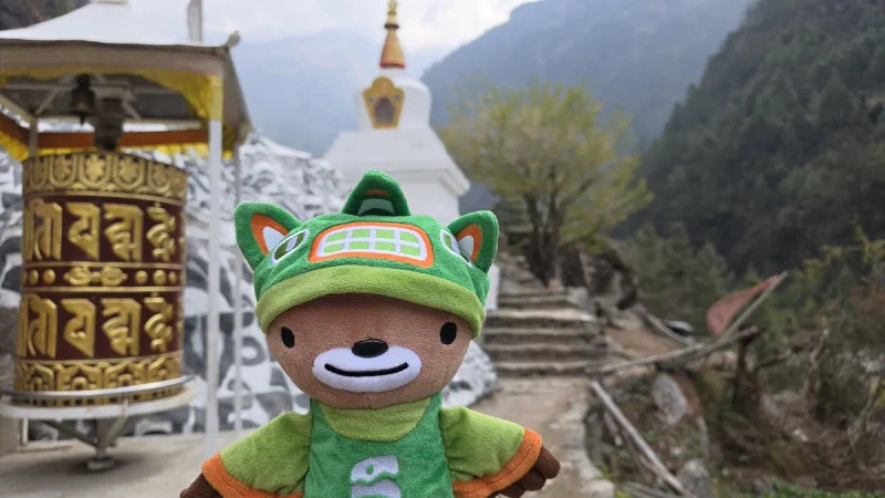 Sumi Bear next to a golden prayer wheel and white stupa