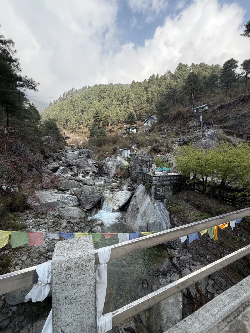 View upstream with rushing river, prayer flags, and lodges