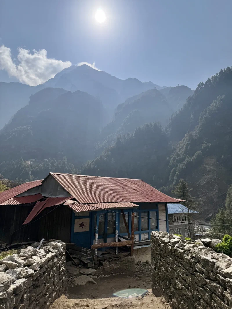 Rustic building with stone walls and mountain peaks in the background