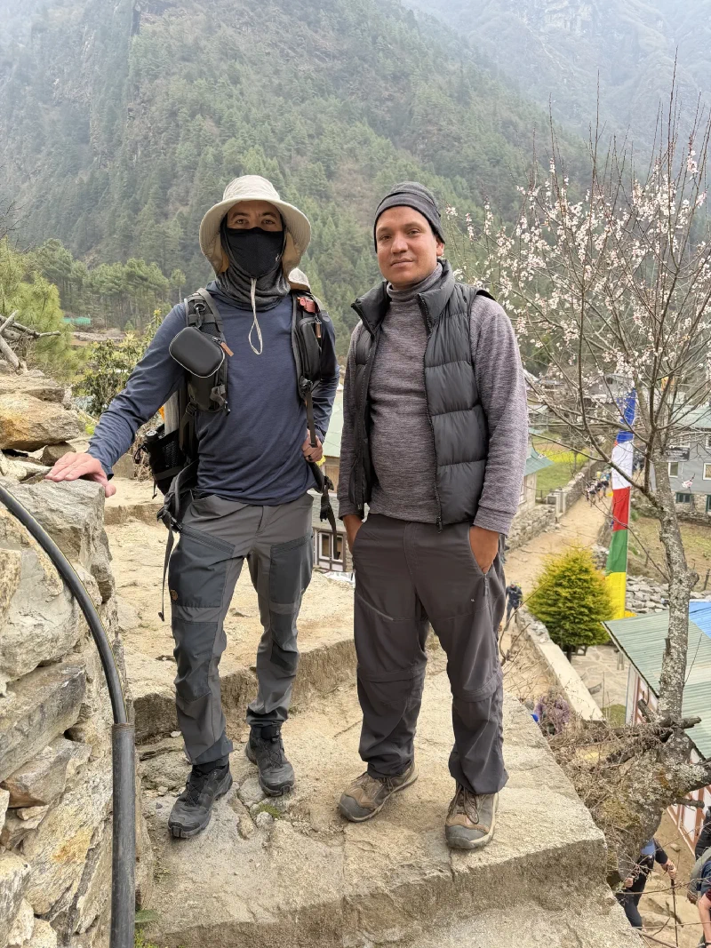 Nicholas and Manoj posing together with blossoms behind them