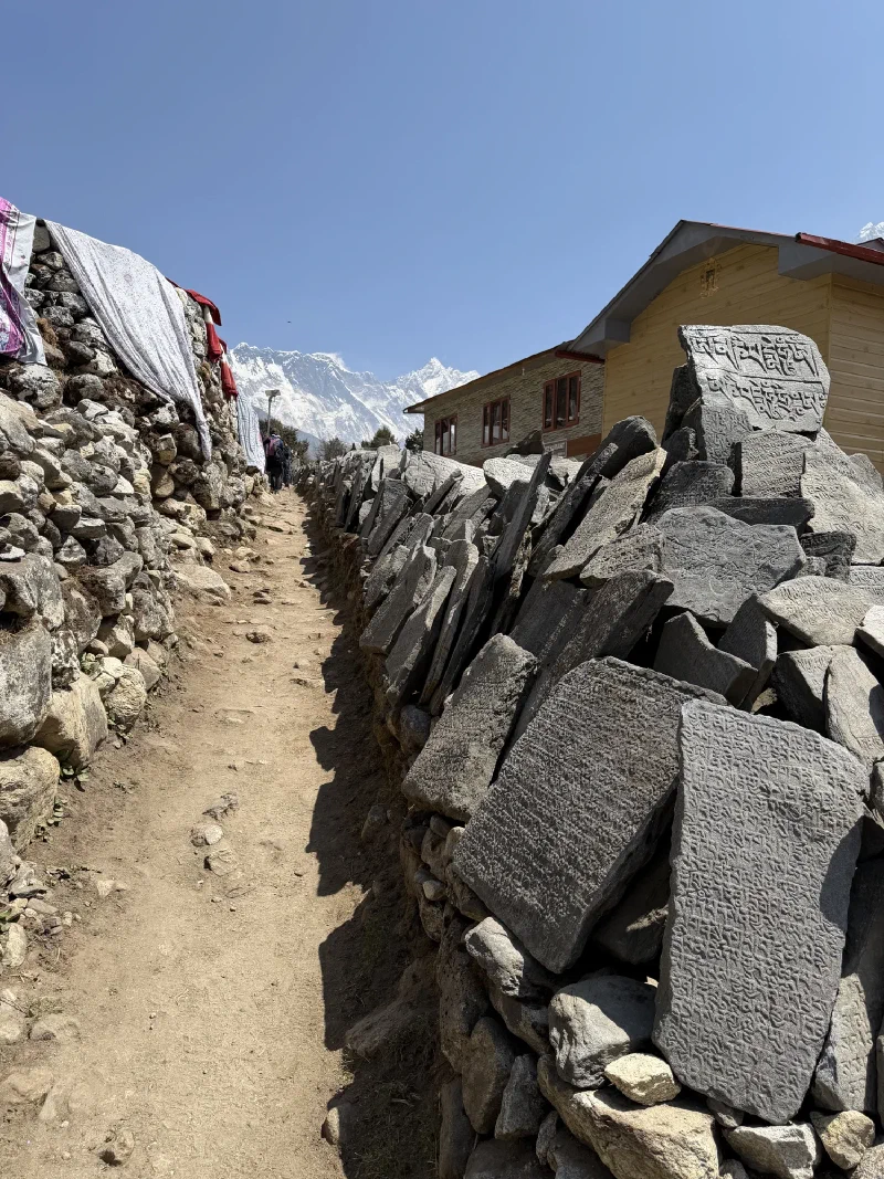 Narrow path with mani wall and snow-capped Himalayan peaks