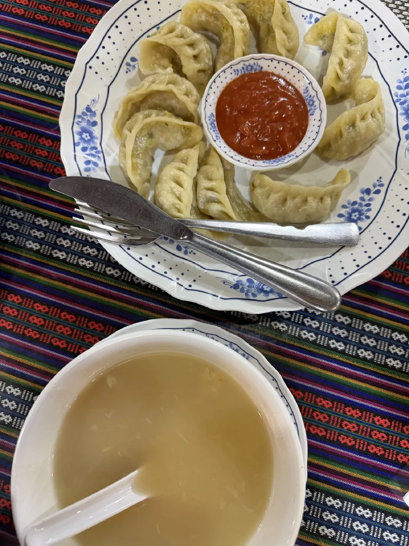 Steamed momos with questionable ketchup on a colorful Nepalese tablecloth