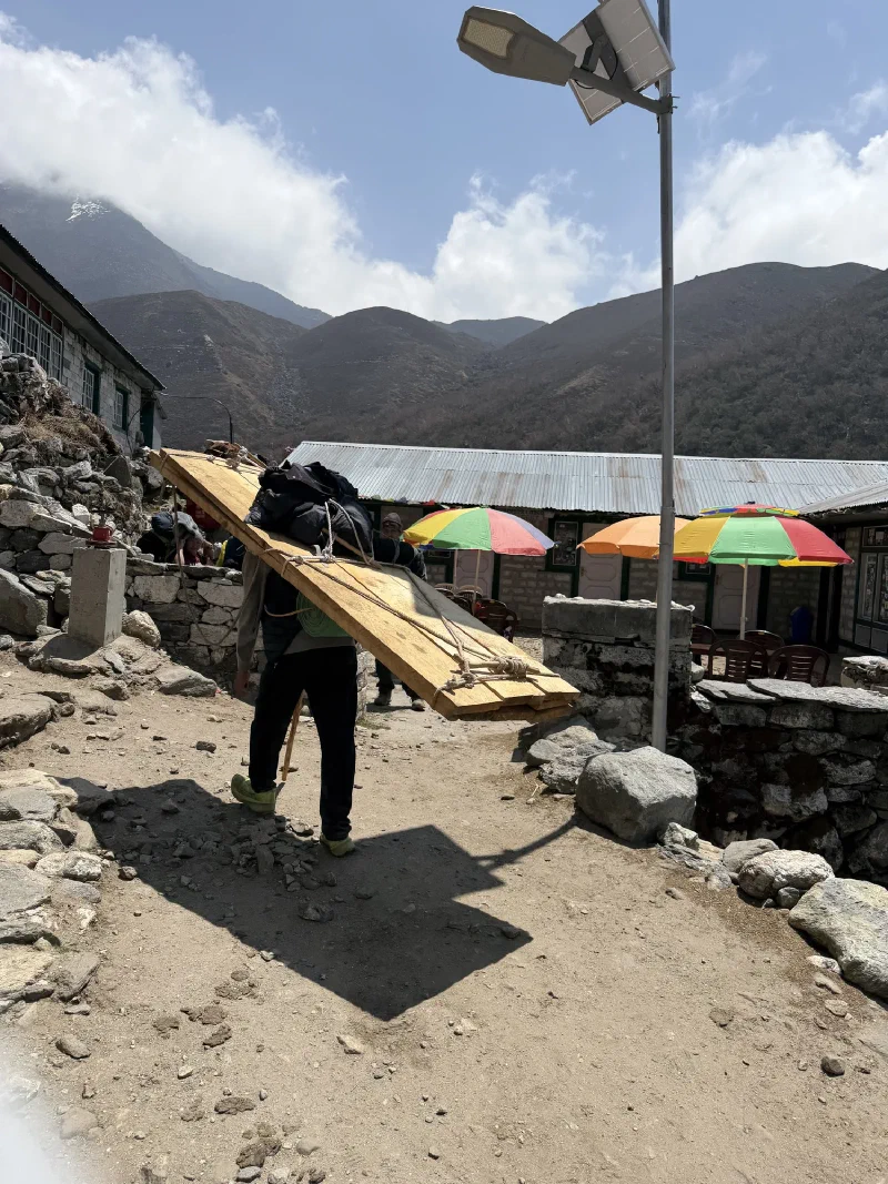 Porter carrying wooden planks on their back