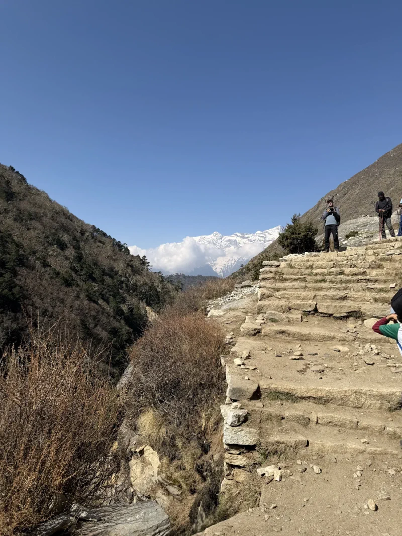 Steep stone stairs with snow-capped peaks visible through the gap