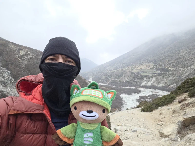 Nicholas in red jacket holding Sumi with misty valley behind