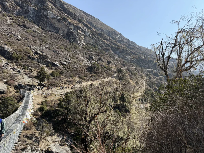 Switchback trail on steep mountainside with tiny hikers visible