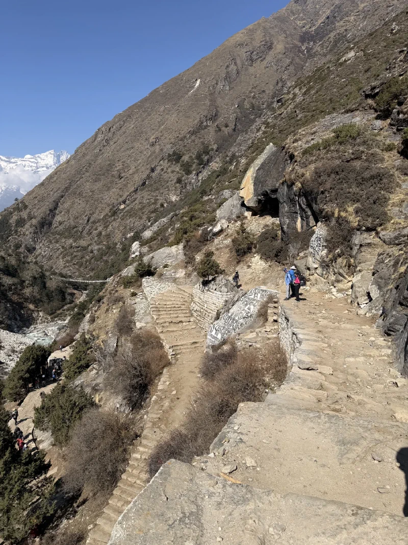 View down switchbacks with mani stone and suspension bridge in distance