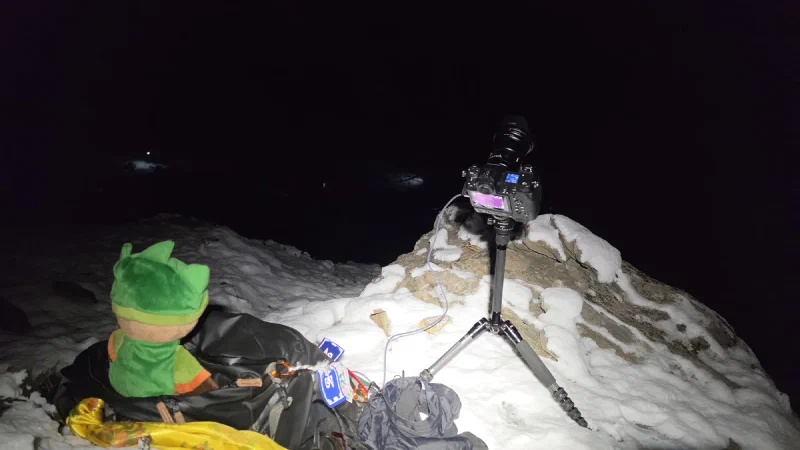 Sumi and camera on tripod in the snow at night near the stupa