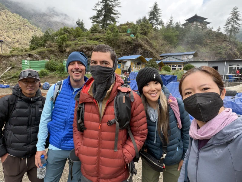 The group bundled up, waiting outside the foggy Surke settlement, taking a selfie
