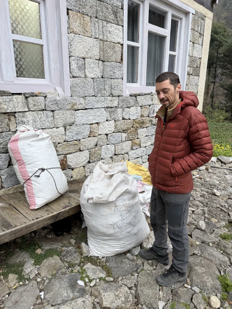 Nicholas standing beside two huge bulging white sacks tied with cord against a stone wall