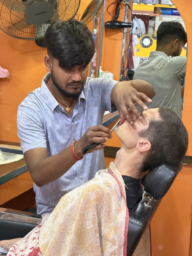 Close-up of a barber holding a straight razor to Nicholas's neck