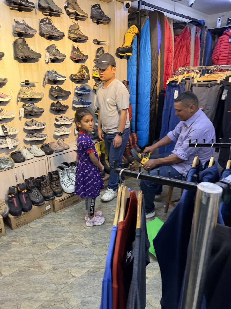 Manoj trying on a pair of new hiking boots in the store