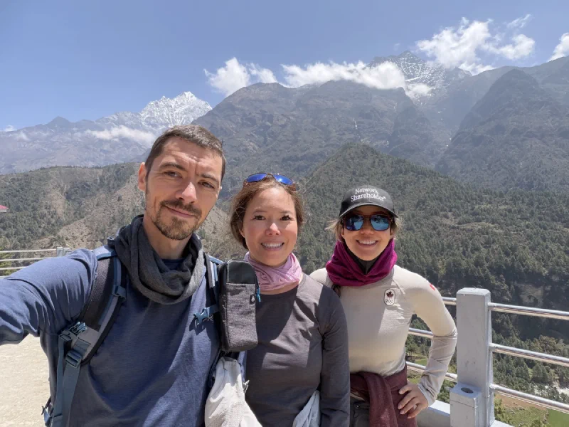 Nicholas, Pokin, and Po On posing at a viewpoint with snow-dusted mountains behind