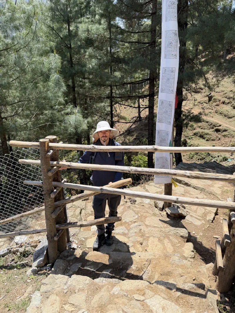 Nicholas standing behind a rustic wooden livestock gate on the trail, hands resting on the bars