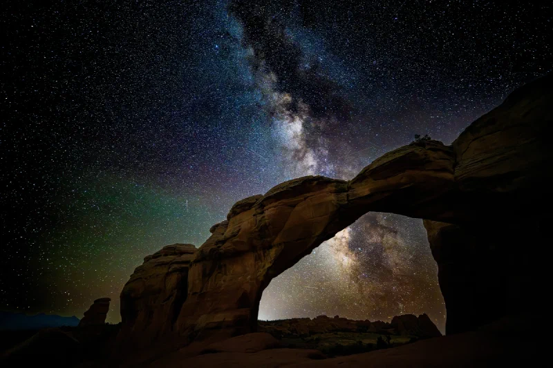 The Milky Way rising directly above and through the opening of Broken Arch under a dense field of stars